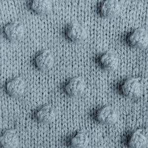 A swatch of knitting demonstrating the bobble stitch in light blue yarn. Knit by KnitQ.