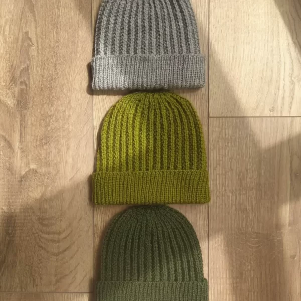 Three one more mistake beanies stacked, with shadows stretching across