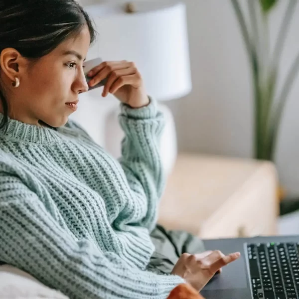 focused young ethnic woman with credit card and laptop