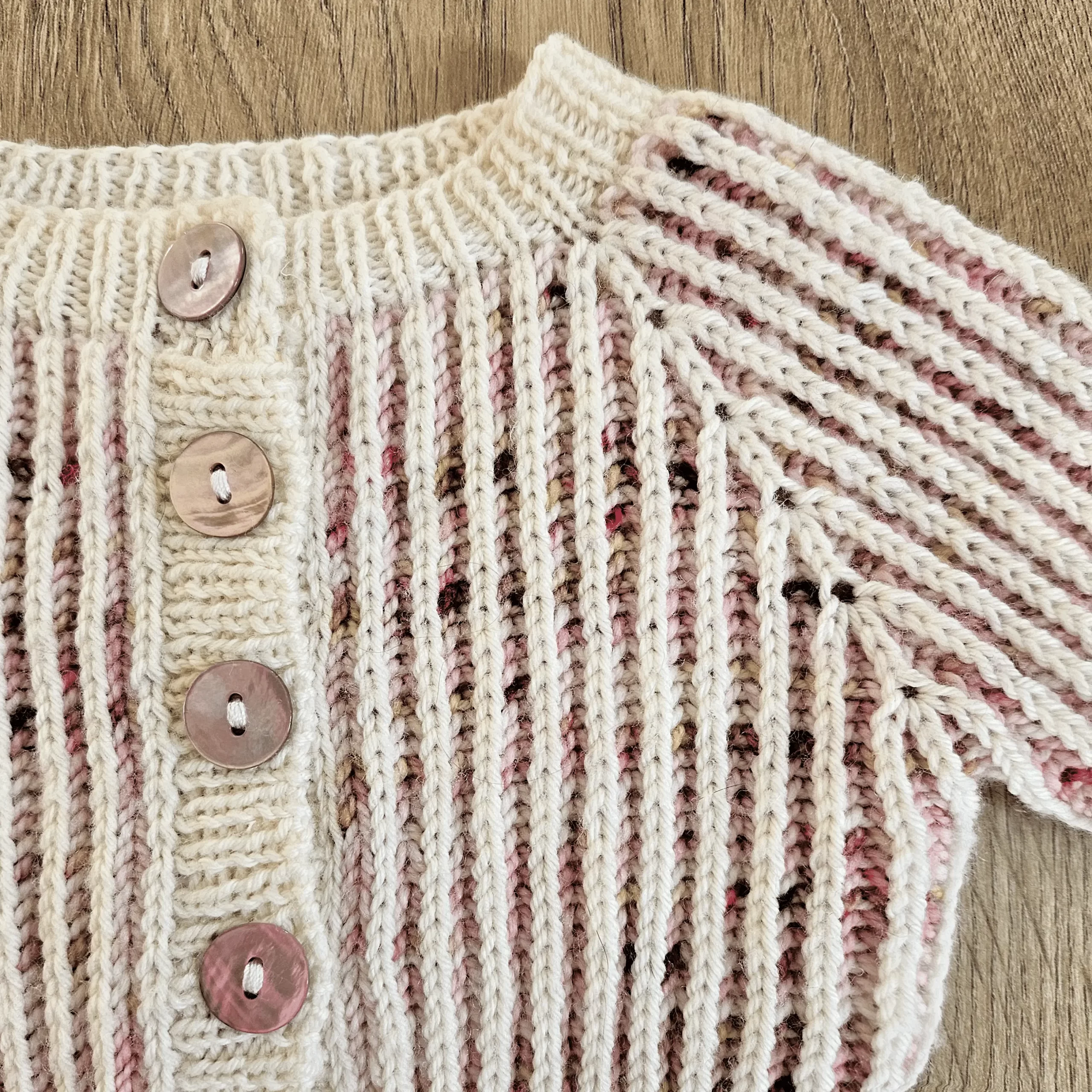 a closeup view of the brioche stitch and buttons used on the Marionberry newborn cardigan