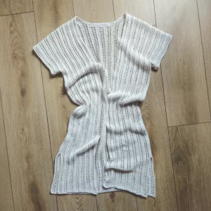 The Reya Swimsuit Cover-up laid out on a wood floor with some gentle wrinkles to show the drape