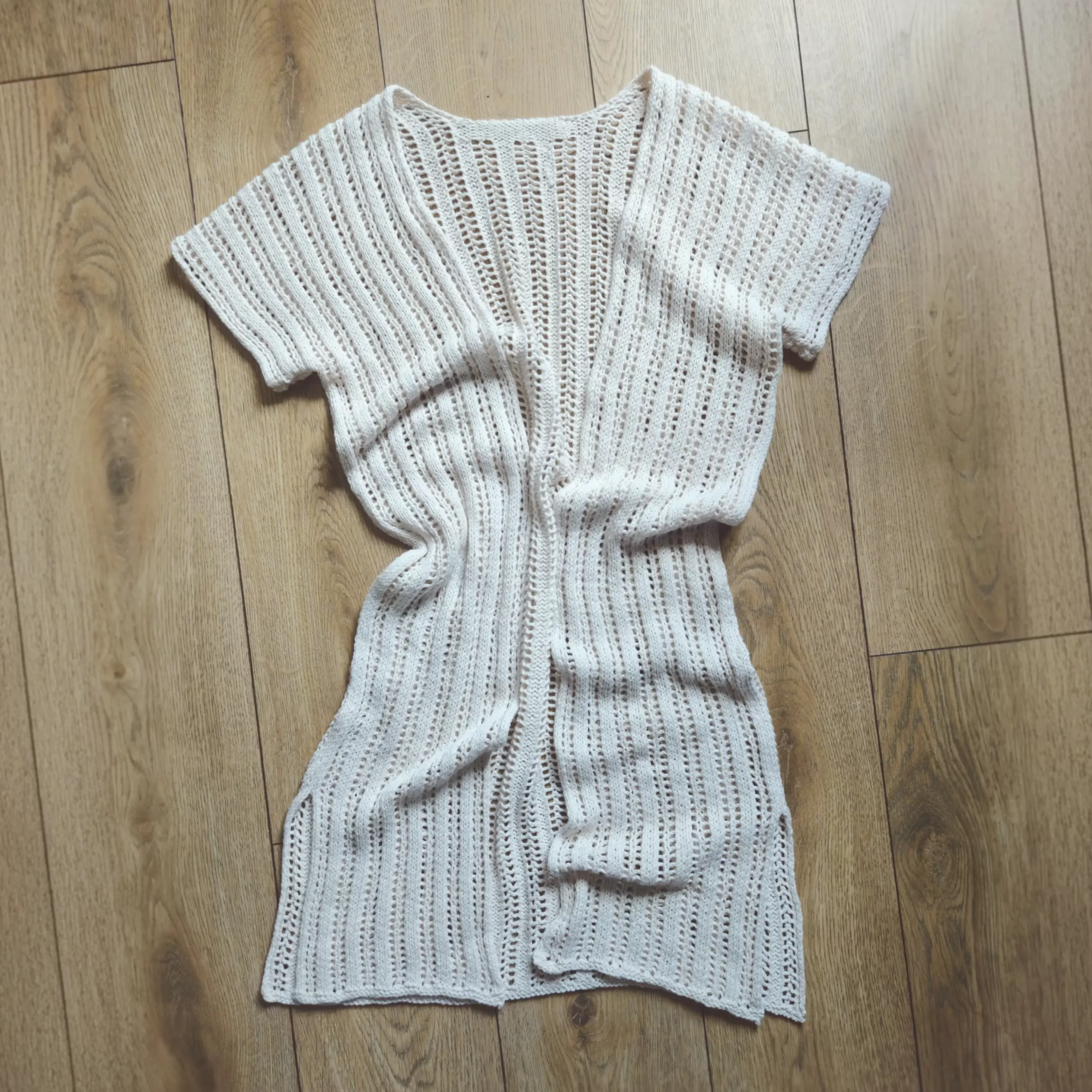 The Reya Swimsuit Cover-up laid out on a wood floor with some gentle wrinkles to show the drape