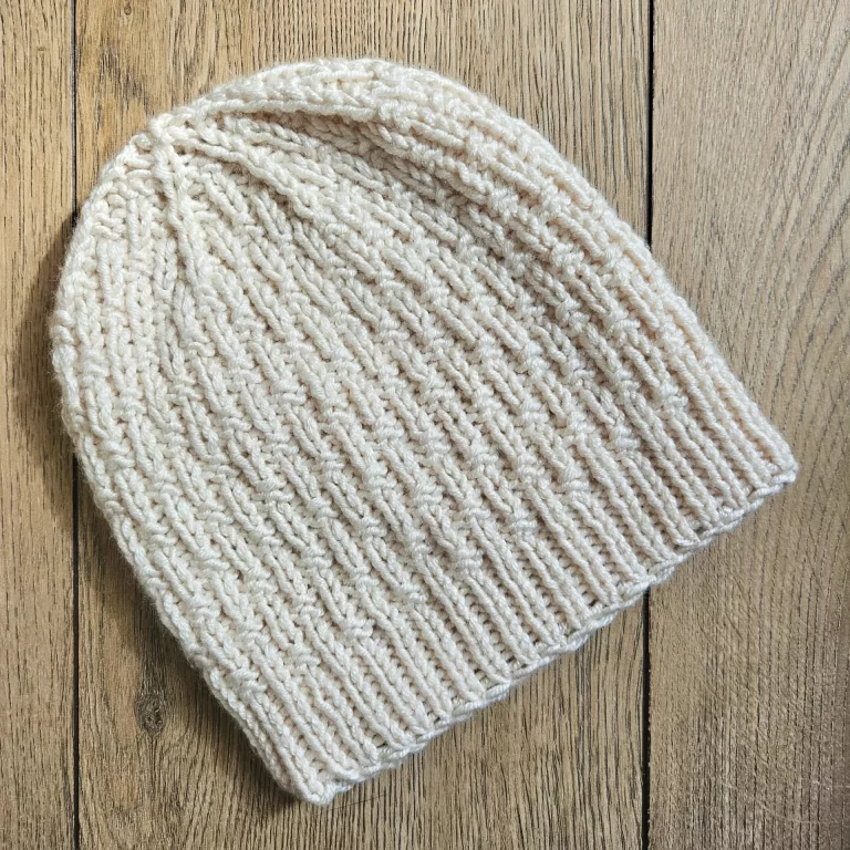 A flatlay photo of the single basketweave beanie on a wood backdrop