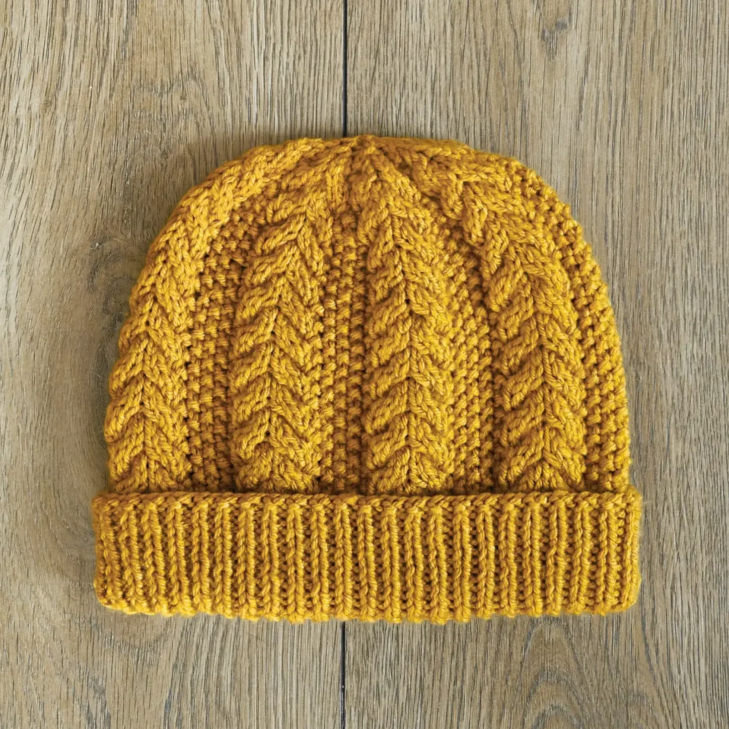 the rusk beanie laying flat on a pale wood floor.